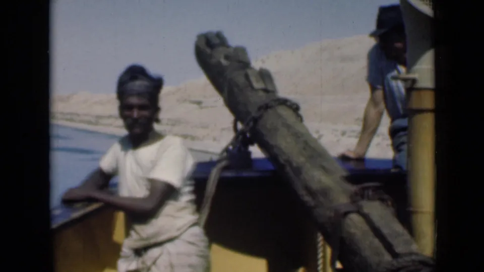 1946 Suez Canal home-movie frame showing a man by the boat rail, with a large pole and a second man partly visible at the stern.