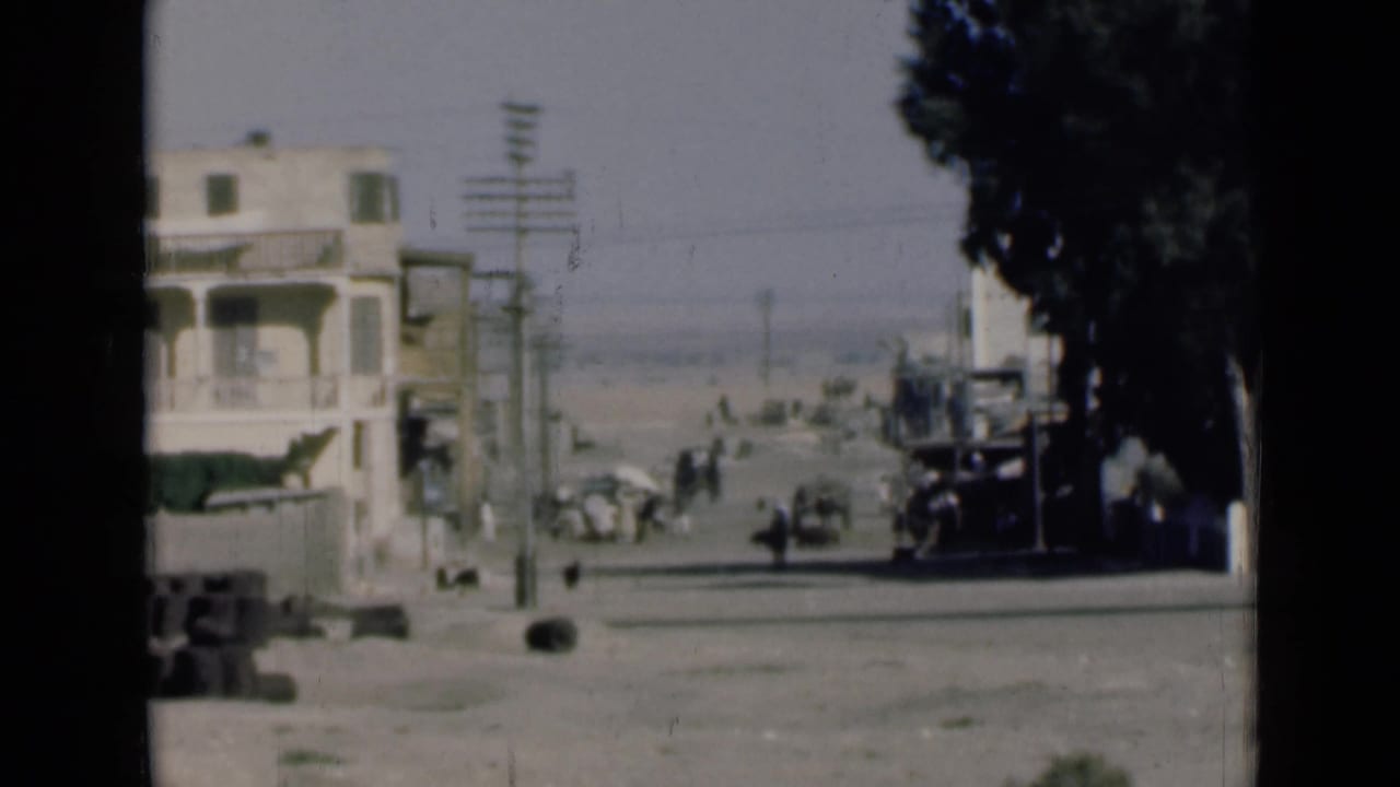 1946 Egypt street view near the Suez Canal with a pale building, roadside trees, utility poles, pedestrians, and early vehicles.