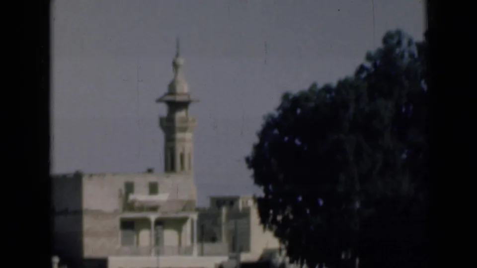 1946 Suez Canal, Egypt frame with a mosque minaret rising behind low buildings and a large tree at right.