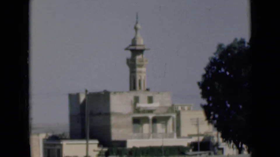 The moving-vehicle view shifts lower, showing more of the roadside wall beneath the minaret-topped building in the Suez Canal area.