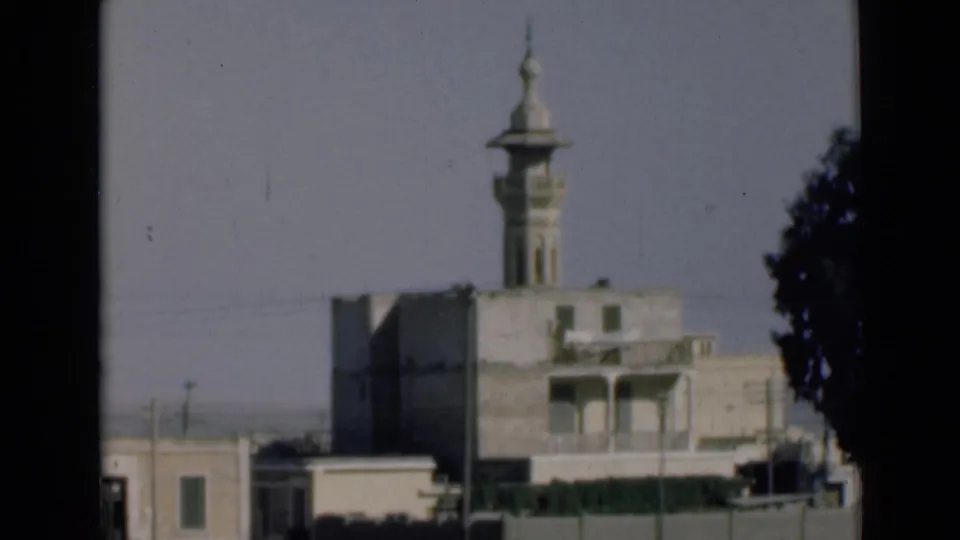 Final frame from the 1946 Suez Canal area clip shows the minaret still visible as roadside buildings and a large tree slide through the view.