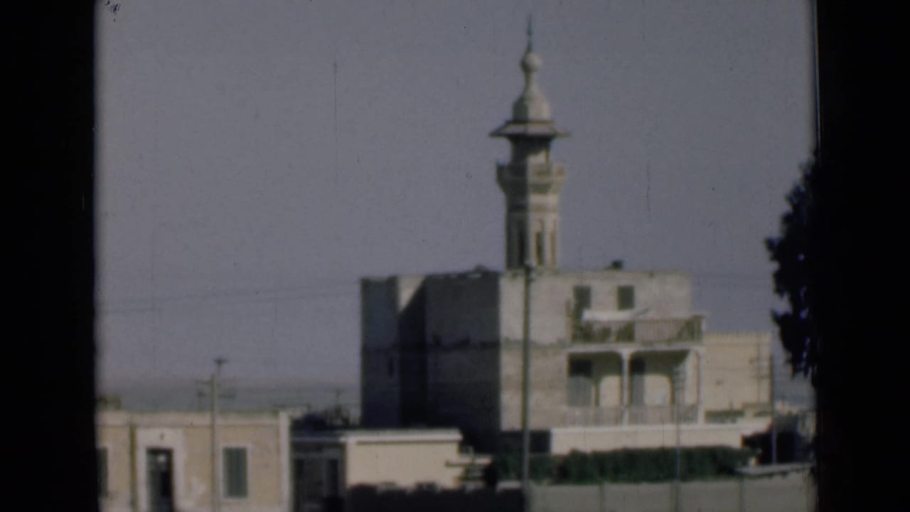 1946 Suez Canal, Egypt home-movie view of a tall mosque minaret rising above low pale buildings through a dark window-like frame.