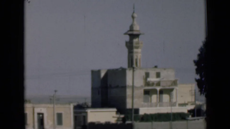 1946 Suez Canal, Egypt home-movie view of a tall mosque minaret rising above low pale buildings through a dark window-like frame.