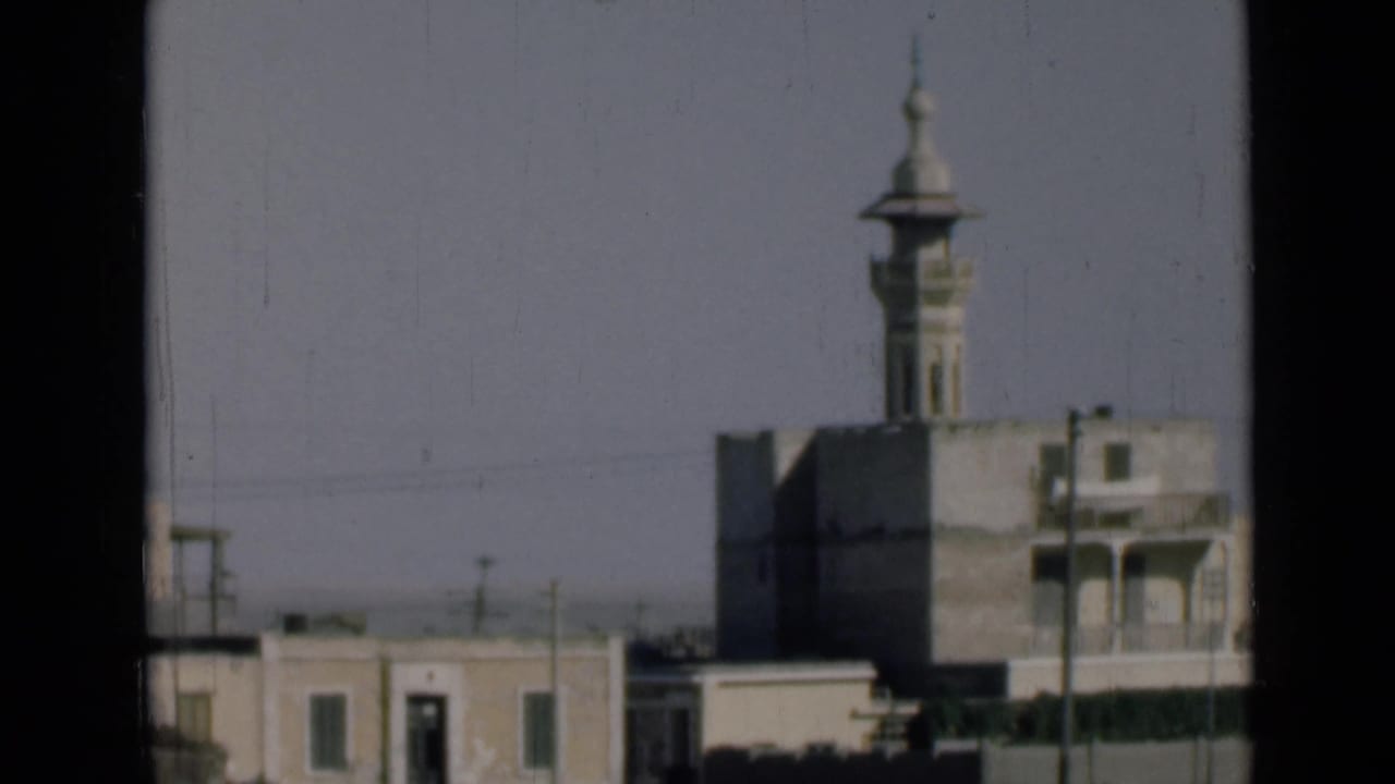 A moving 8mm view in the Suez Canal area shows a minaret above surrounding buildings, partially bordered by dark window framing.