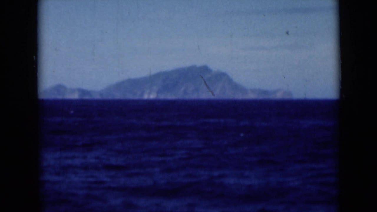1946 Suez Canal-area footage shifts to blue water in the foreground and a hazy distant landmass across the horizon.