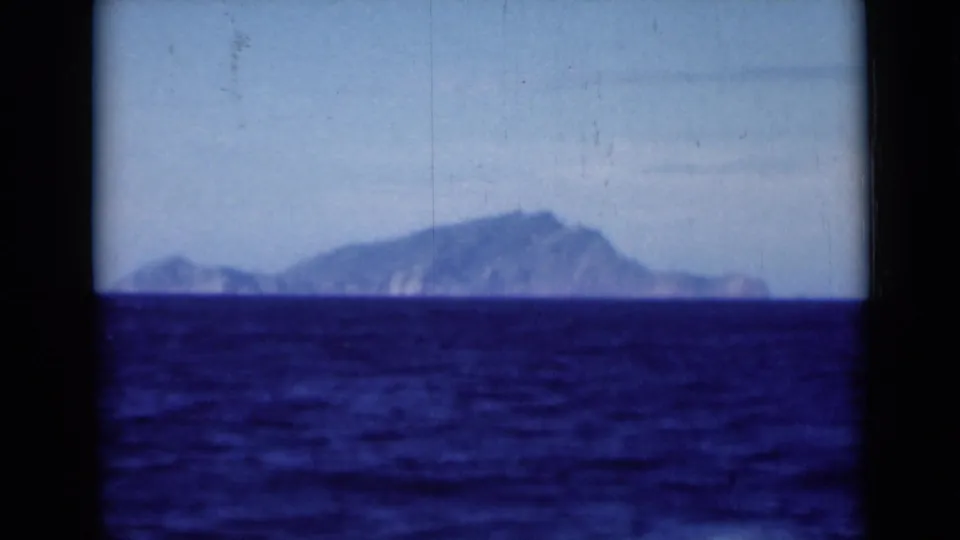 1946 8mm Suez Canal region footage showing a hazy mountainous landform viewed from a vessel across deep blue water.