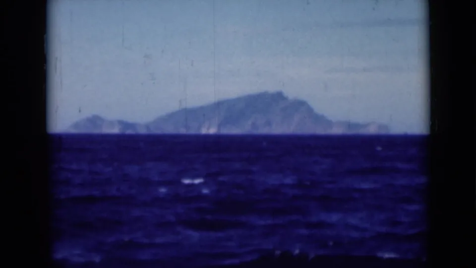 Vintage 8mm maritime frame from the 1946 Suez Canal metadata, showing a sloping distant landform across a textured sea.