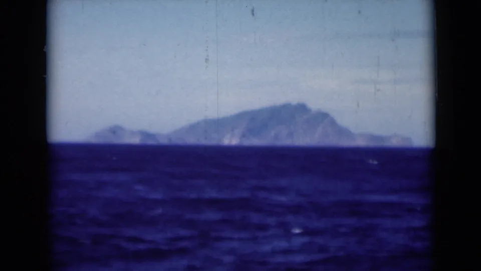 1946 shipboard home-movie frame near the Suez Canal region, with blue sea leading to a hazy mountainous shoreline.