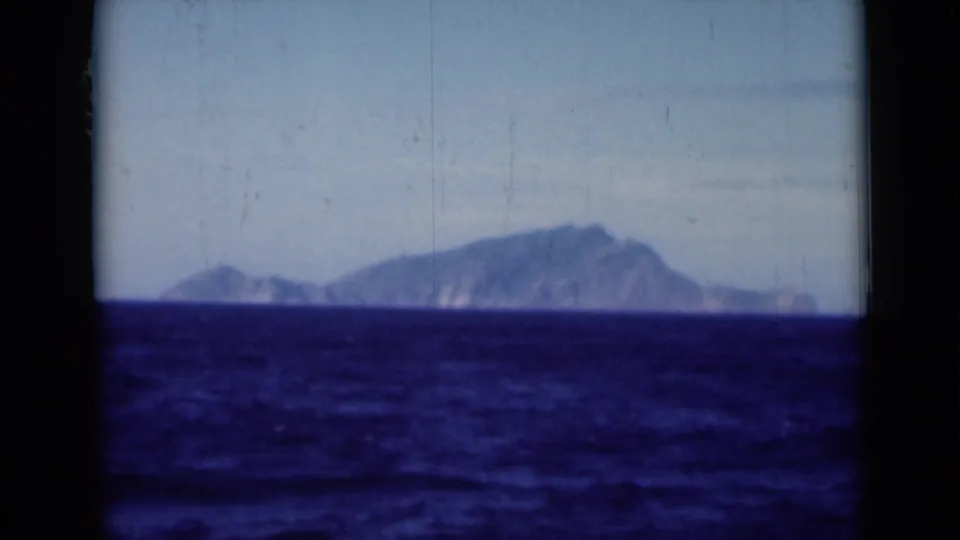 1946 Suez Canal area home-movie frame showing a distant landmass beyond dark blue water, framed by ship-window edges.