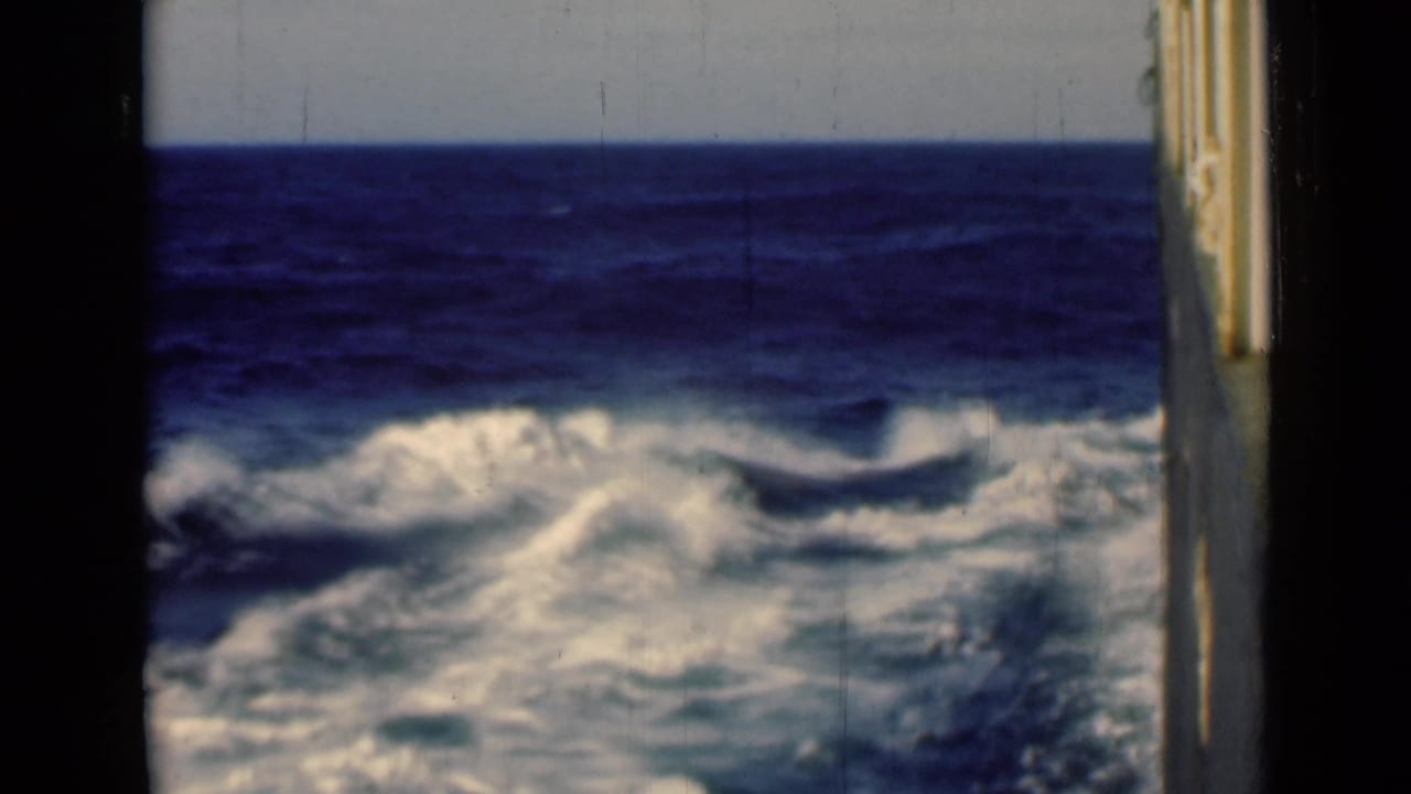 White foam churns beside a moving vessel under a clear sea horizon.
