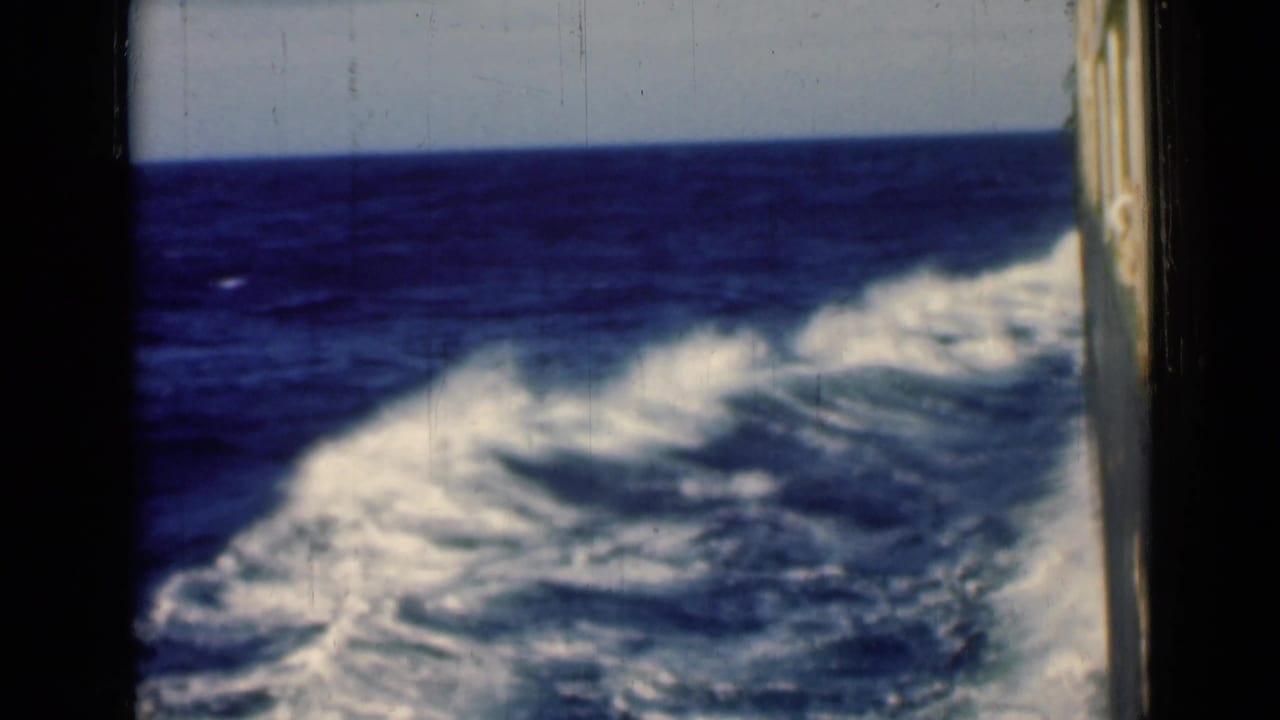 1946 shipboard 8mm view near the Suez Canal context, showing foamy blue wake trailing across the sea under a pale horizon.