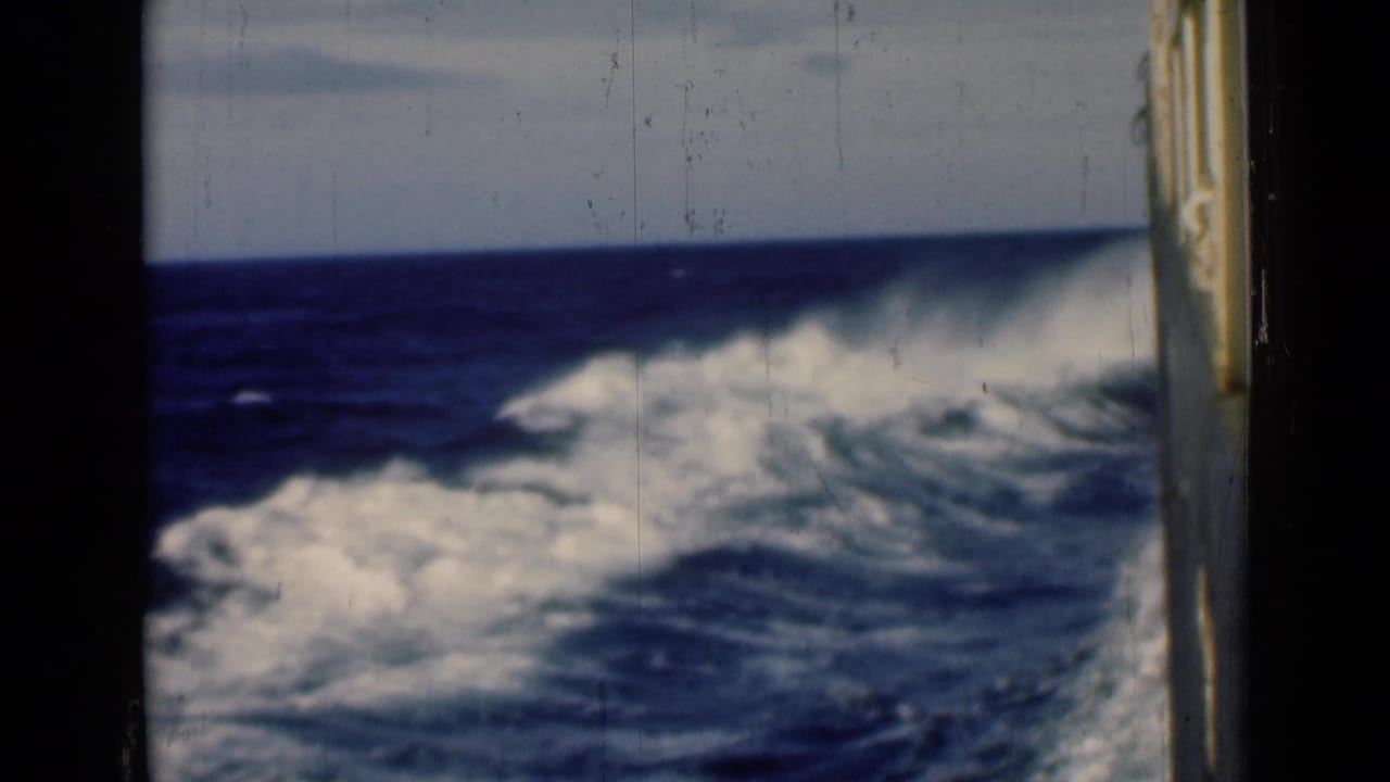 Churning sea wake beside a ship with a vertical edge at the right.