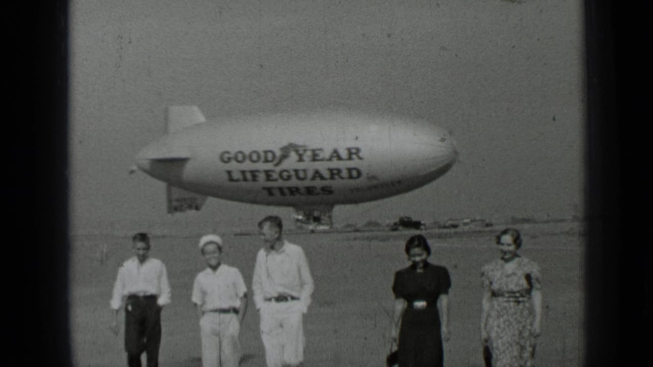 In 1937 San Francisco home-movie footage, five people walk on an airfield in front of a Goodyear Lifeguard Tires blimp.