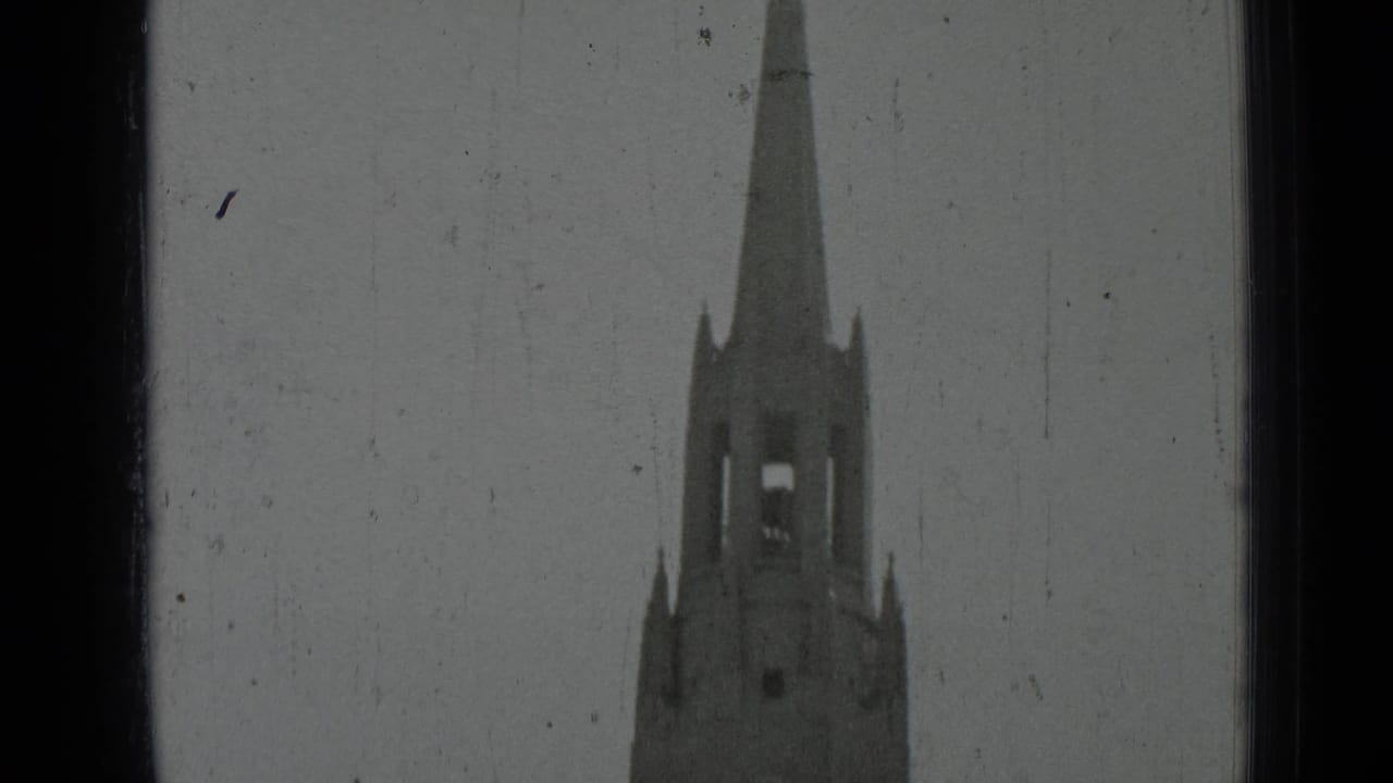 Pointed spire and upper bell tower framed against a light sky.