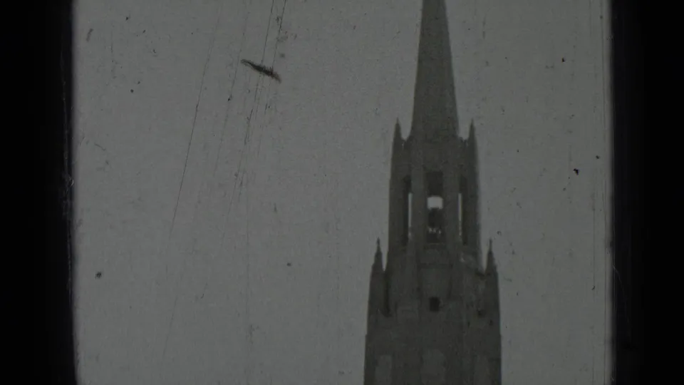 1937 San Francisco 8mm frame showing the cathedral tower, long spire, arched bell openings, and visible film wear.