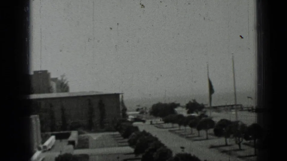 1937 San Francisco home-movie view across low buildings, trees, and a walkway, partly obscured by dark 8mm frame edges.