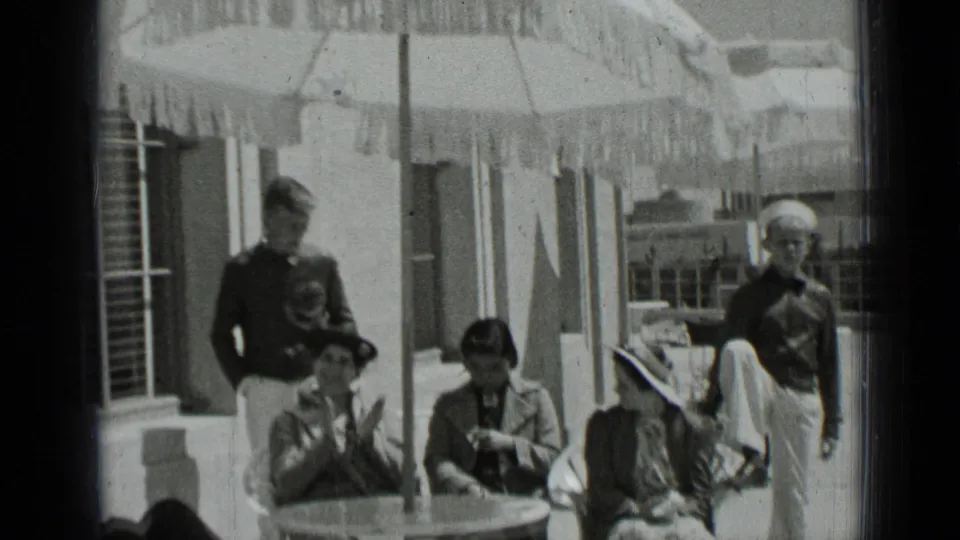 Women in hats and sailors in uniform gather around an outdoor patio table in the stated 1937 San Francisco footage.