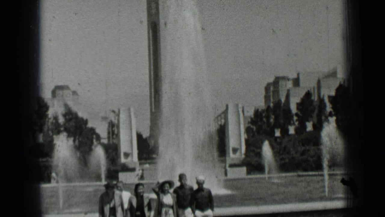 1937 San Francisco home-movie frame showing young adults walking near fountain jets and modernist park structures.