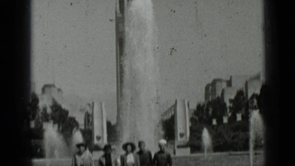 Black-and-white 8mm frame with visitors near fountains in a San Francisco park, partly cropped by the film frame.