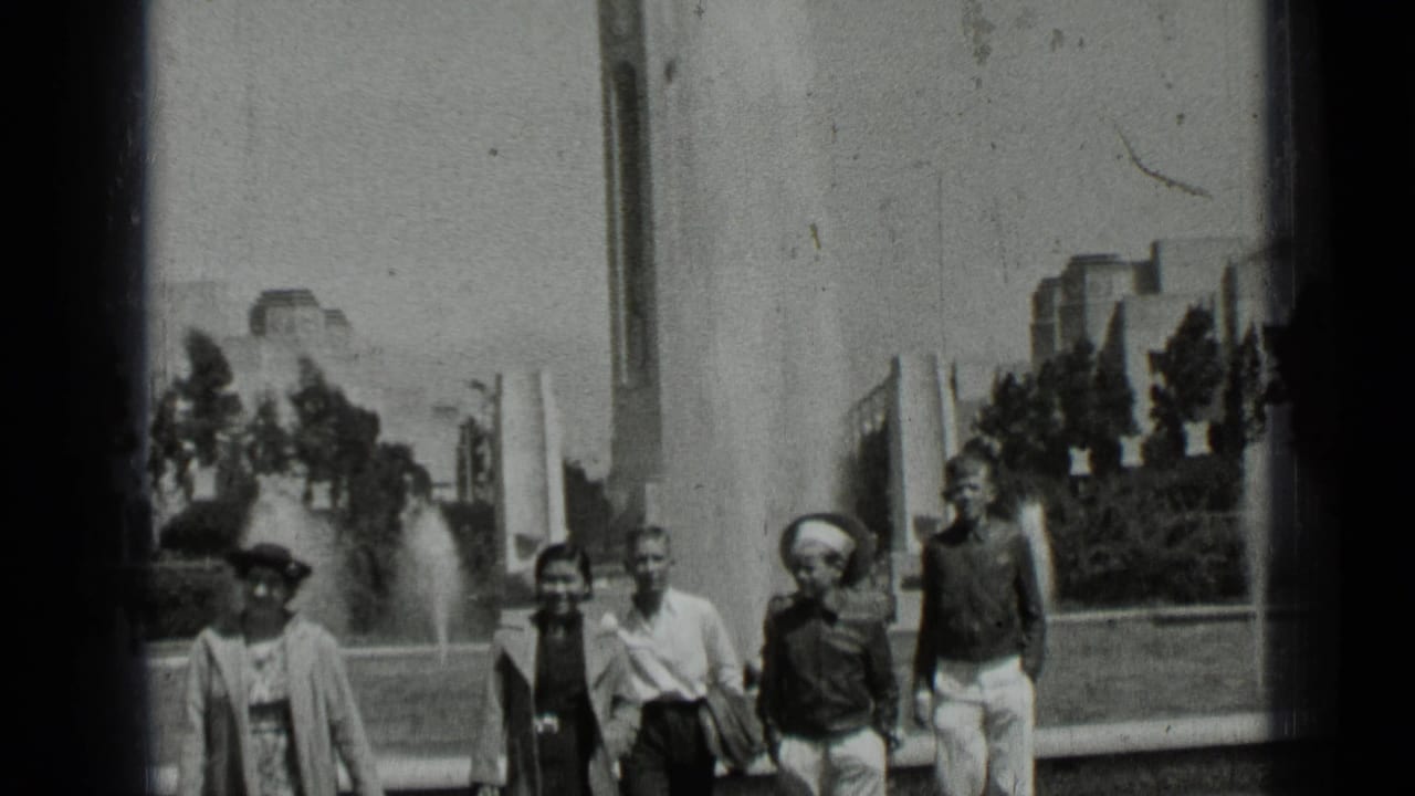 Group of people walking toward the camera beside a park fountain.