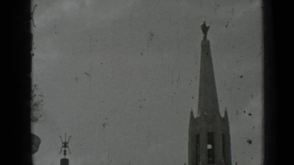 1937 San Francisco home-movie frame with a tall park monument or spire rising against a bright sky.