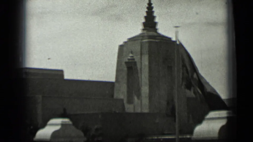 Black-and-white 1937 San Francisco frame showing a stepped tower and a flag with a crescent and star shape nearby.
