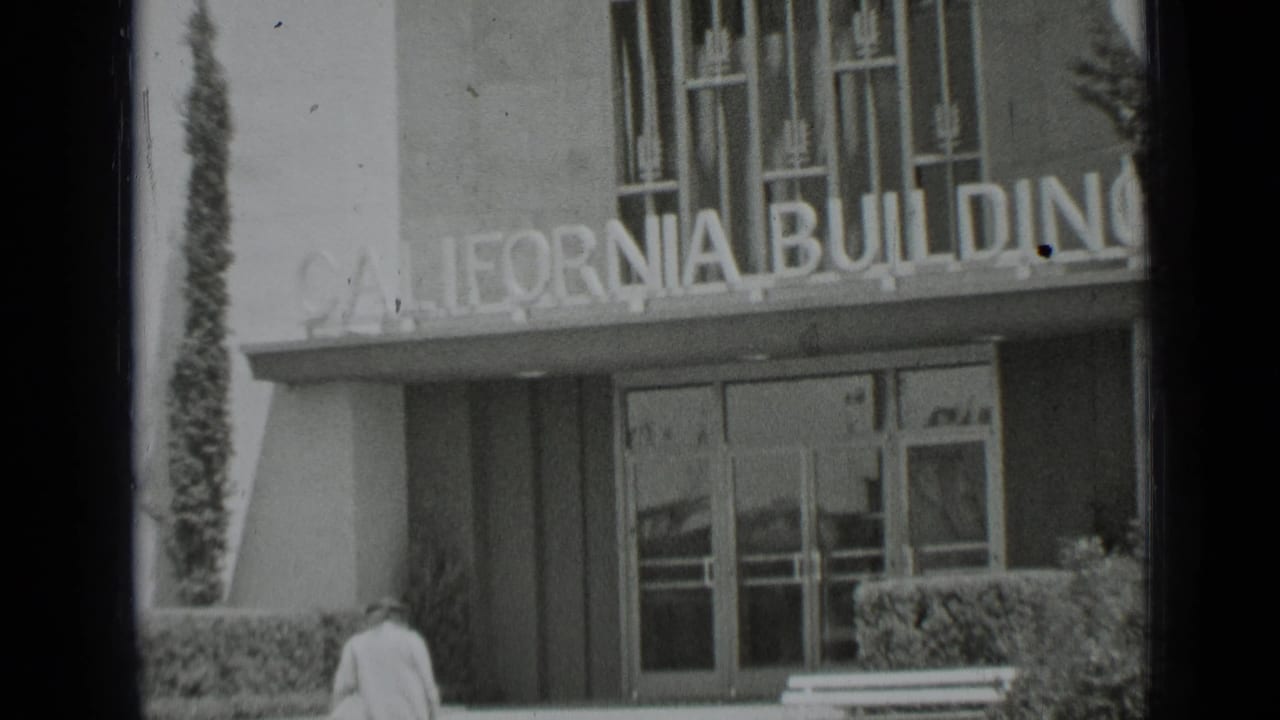 1937 San Francisco frame of the California Building facade and glass doors as a woman nears the entrance area.