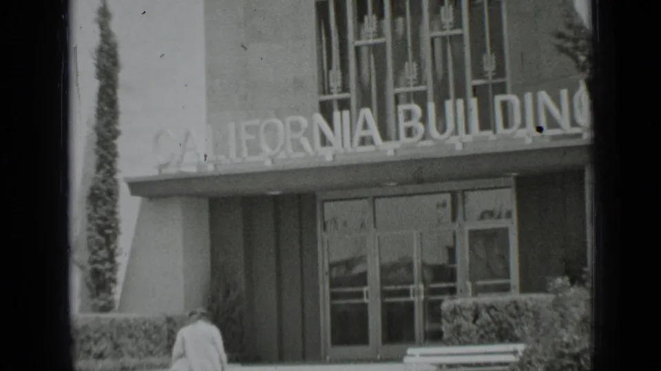 1937 San Francisco frame of the California Building facade and glass doors as a woman nears the entrance area.