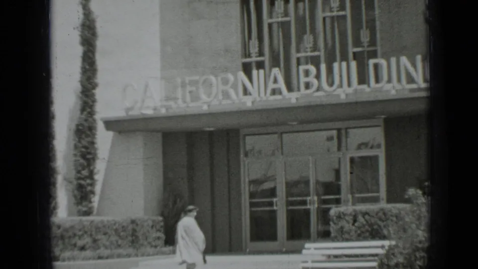 1937 San Francisco home-movie frame showing the woman near the California Building entrance beneath the large sign.