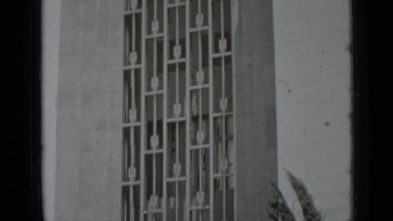 Geometric metal window grille on a pale building facade.