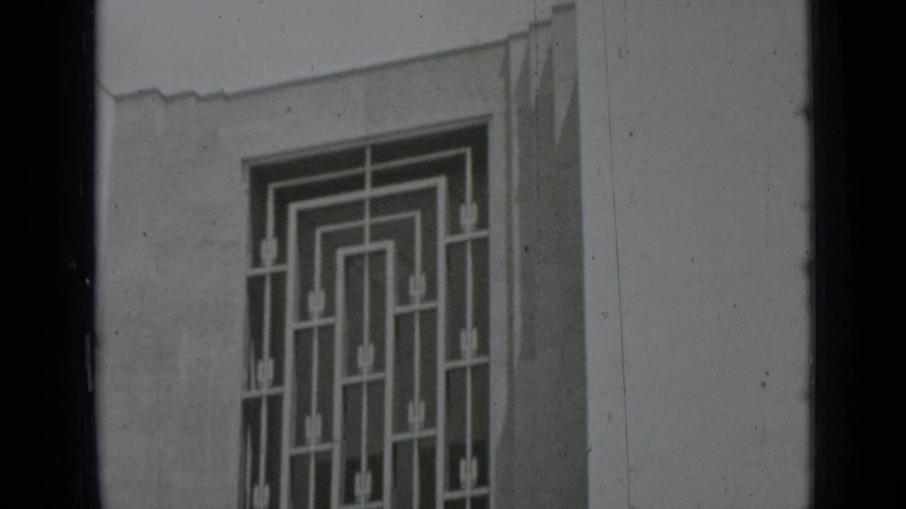 Black-and-white frame of a geometric window grille and pale exterior wall, consistent with the supplied 1937 San Francisco clip metadata.