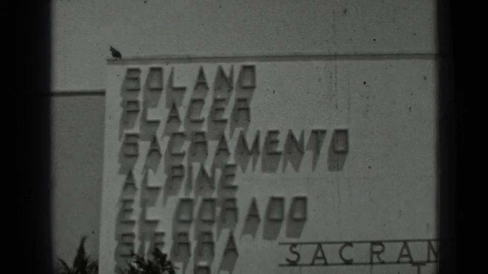 Black-and-white frame of raised facade lettering with California place names, including a partial Sacramento inscription.
