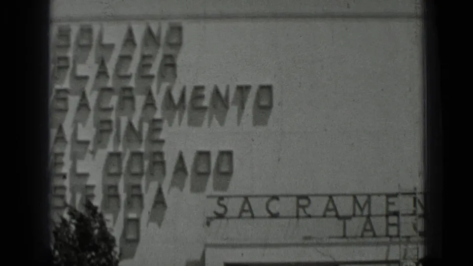 1937 San Francisco 8mm frame showing a cropped storefront facade with partial Sacramento and Tahoe lettering and heavy film-edge shadowing.