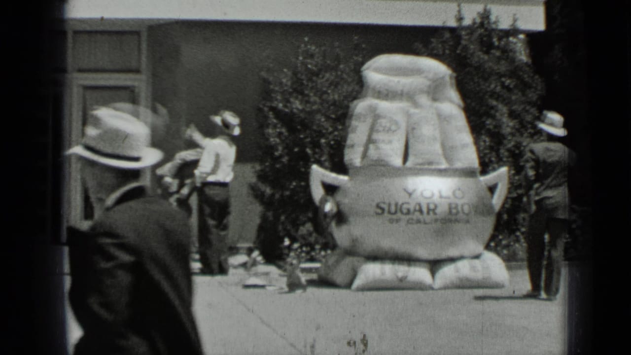 Men stand near a storefront and large YOLO sugar-bag display on a sidewalk.