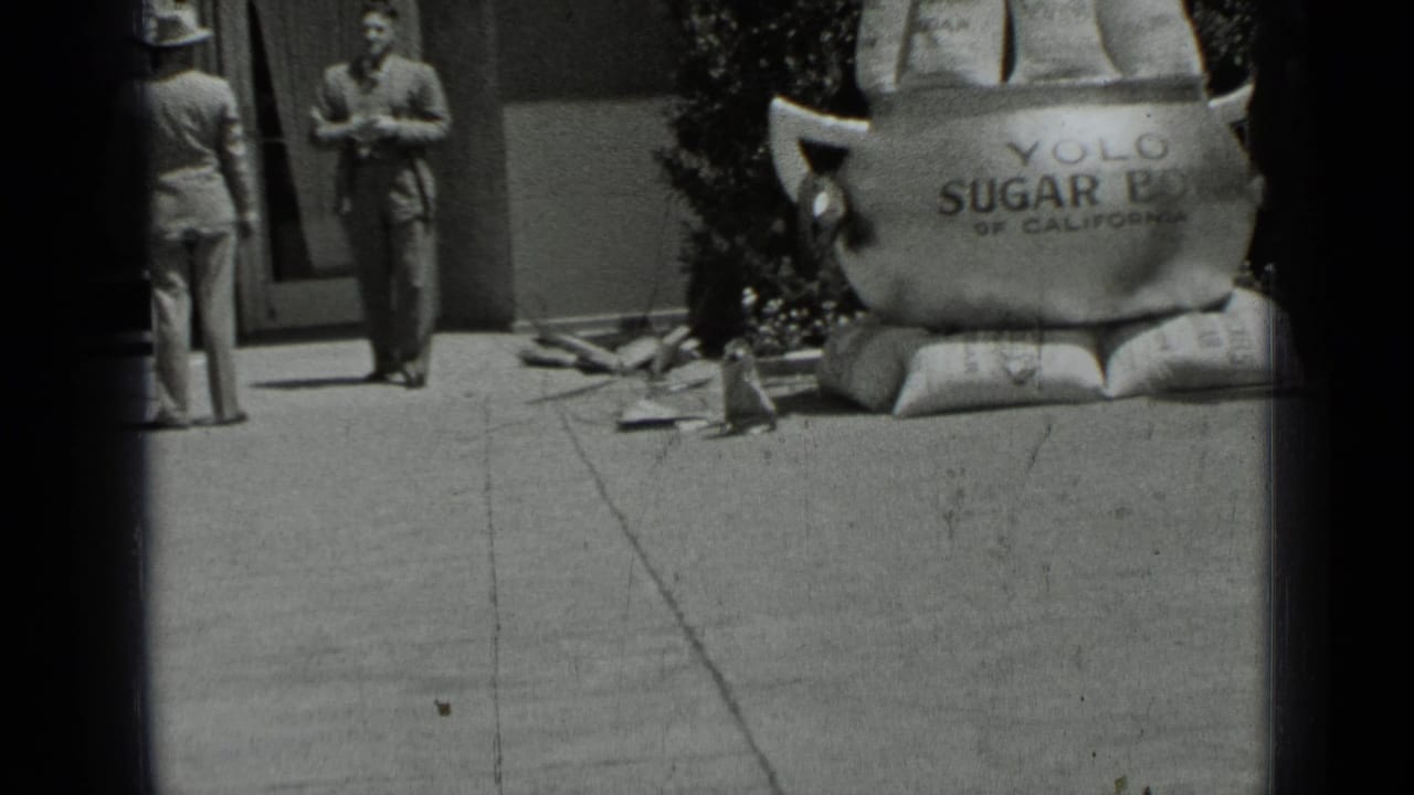 Two men near a large sugar bowl prop outside a building entrance.