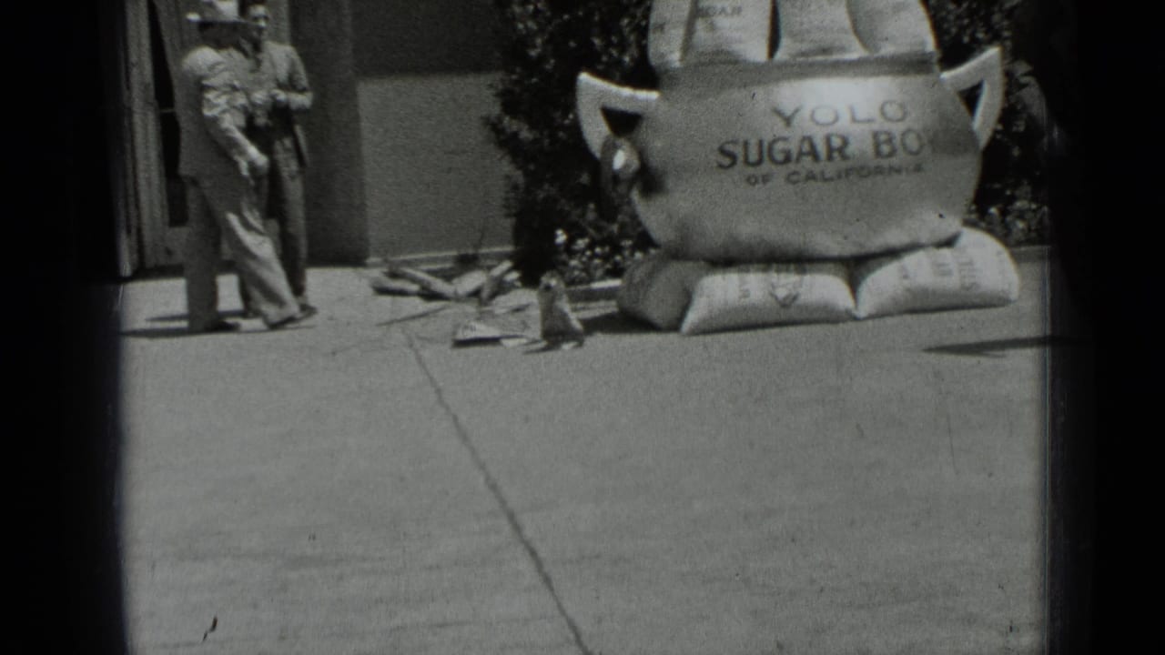 Man holding something while standing beside the oversized sugar bowl display.