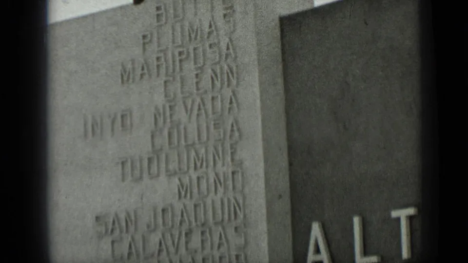 1937 San Francisco frame with engraved names on a stone wall and the beginning of bold ALTA letters on an adjacent facade.