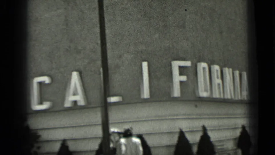 1937 San Francisco view of CALIFORNIA lettering on a building wall, with pedestrians in hats gathered below.