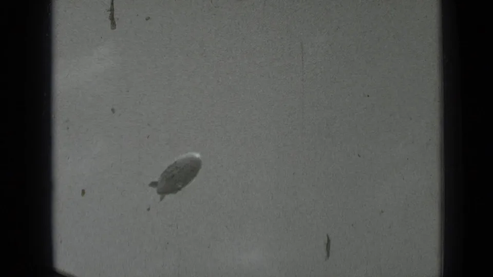 A small blimp appears in the pale sky in this 1937 San Francisco 8mm frame, with visible grain and vertical scratches.