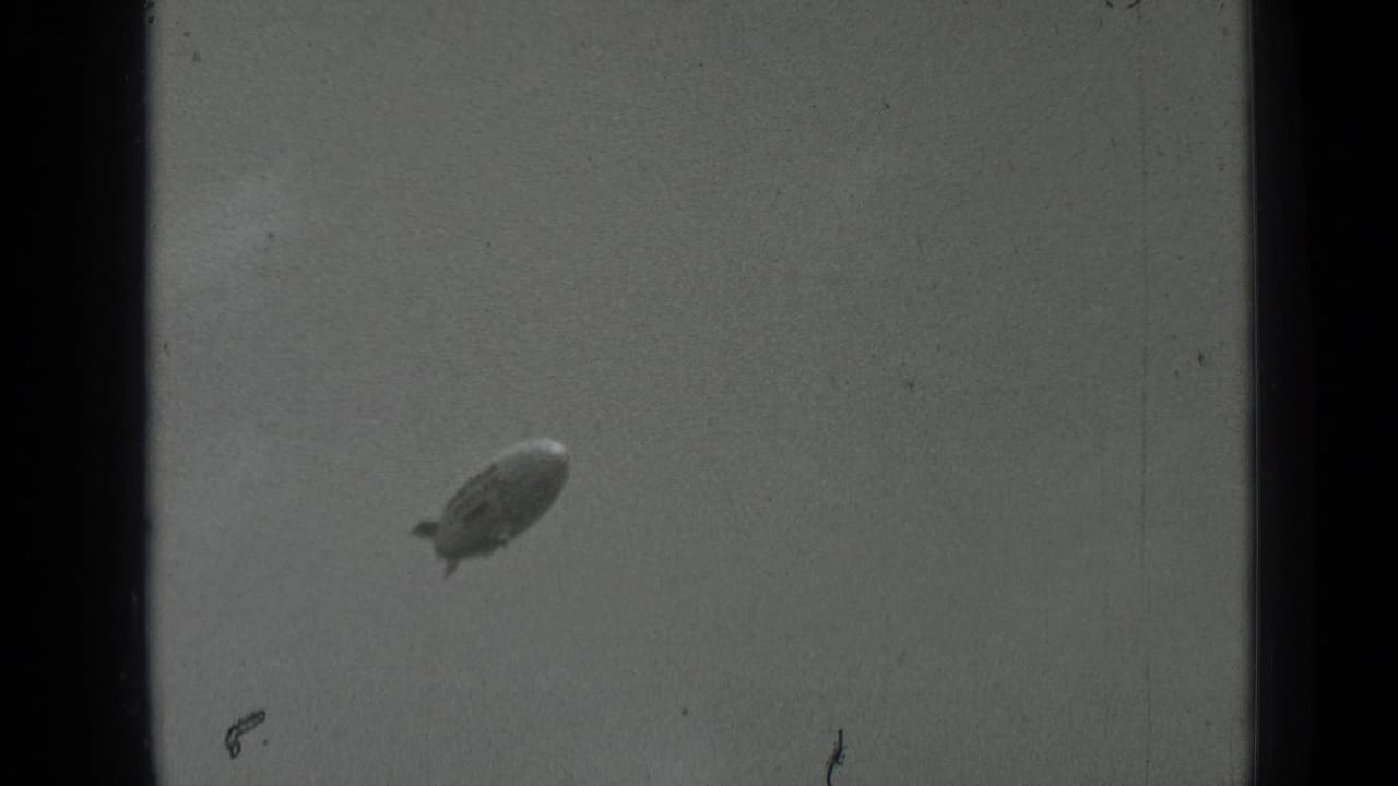 A Goodyear blimp appears at a distance in cloudy 1937 San Francisco 8mm footage, with visible grain and frame edges.