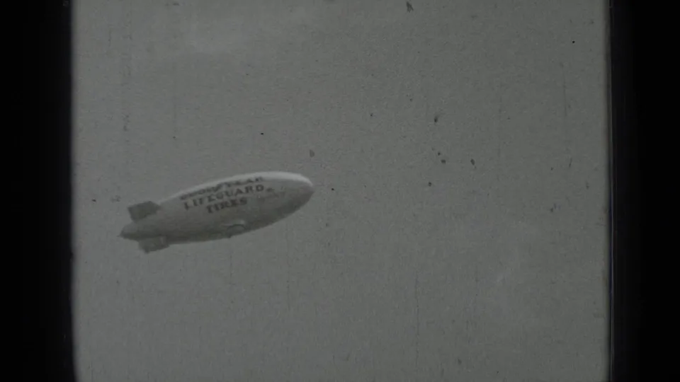 The Goodyear Lifeguard Tires blimp passes closer through the 1937 San Francisco frame, with branding legible on its side.