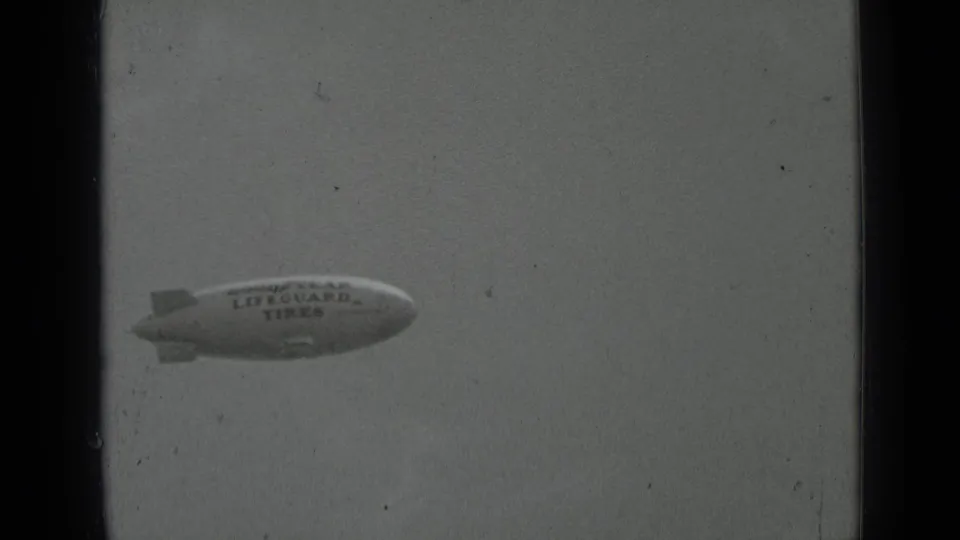 1937 San Francisco 8mm frame showing a distant Goodyear blimp marked Lifeguard Tires against a pale sky.