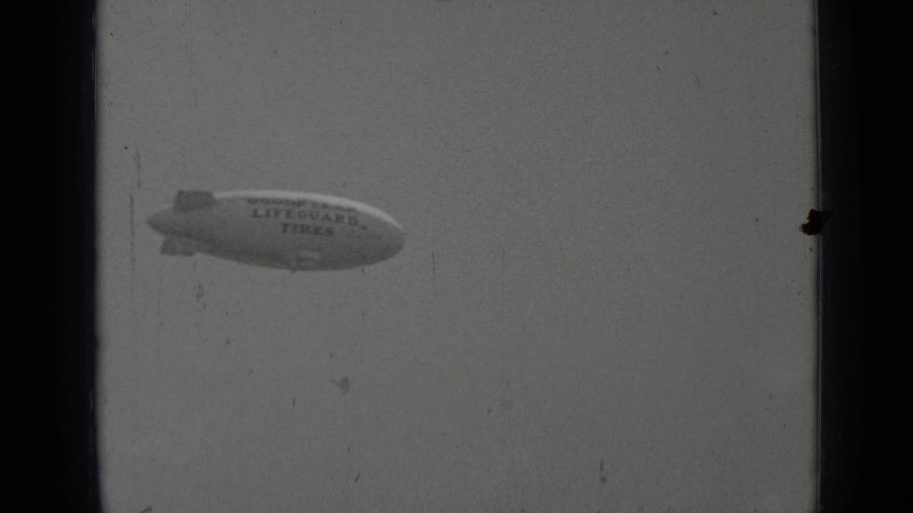 Goodyear blimp with Lifeguard Tires lettering in a hazy sky.