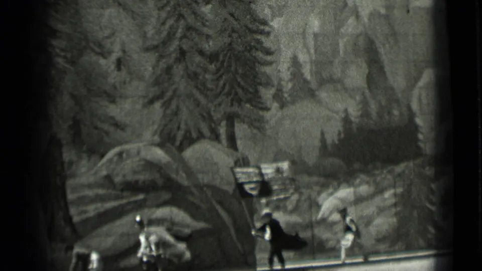 Black-and-white 1937 home-movie frame showing small medieval-style figures and a flag against painted trees and rocks.