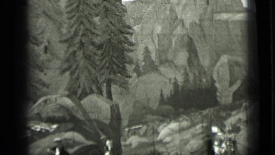 Black-and-white 8mm frame dominated by a painted forest and rocky landscape, with tiny staged figures below.