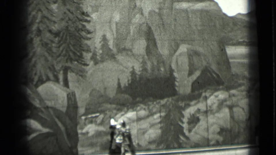 1937 black-and-white home-movie frame with a miniature armored figure centered against a painted mountain landscape.