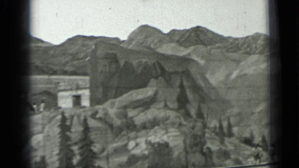 1937 San Francisco 8mm frame showing a wider view of the miniature rocky terrain, painted mountains, and small structure at left.
