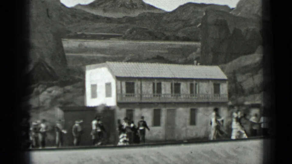 1937 San Francisco frame with performers near a staged building facade, painted mountain backdrop, and trackside edge.