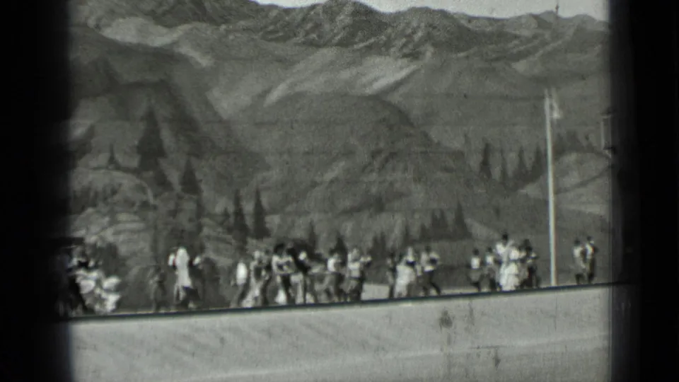 Wide 1937 San Francisco home-movie view of multiple figures spread across a staged mountain backdrop and low foreground edge.