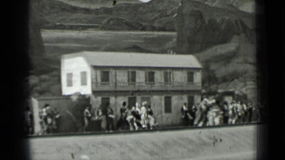 1937 San Francisco home-movie frame showing people in formal dress dancing and watching outside a large two-story building.